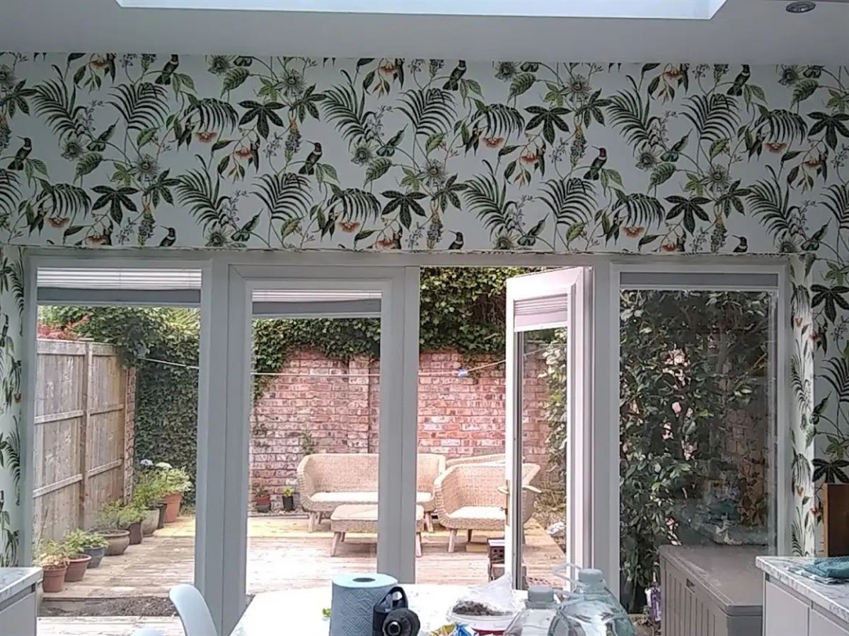 Botanical wallpaper hung around french doors onto a courtyard