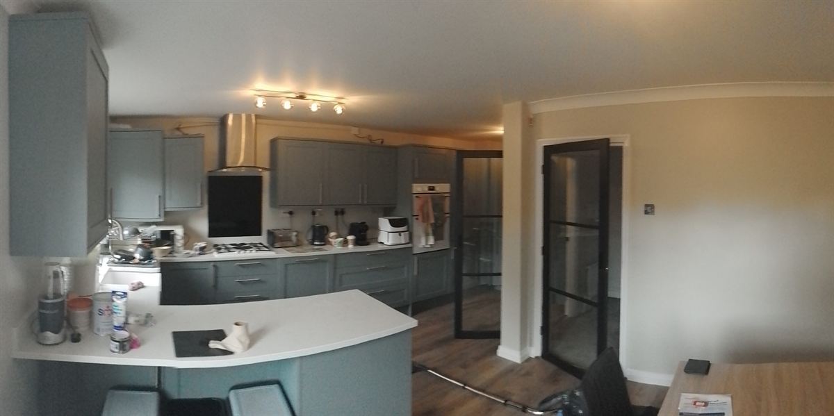 Kitchen with grey units and a black crittall-style door