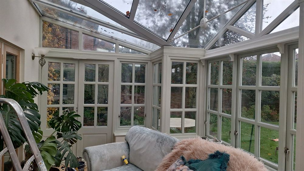 Conservatory interior with repainted timber frames looking out onto a garden