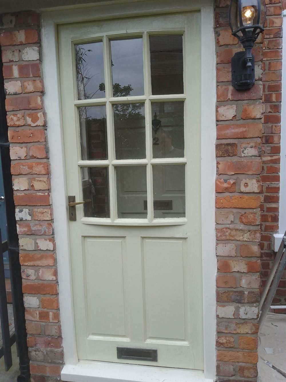 Repainted timber front door with glazing bars in a brick surround