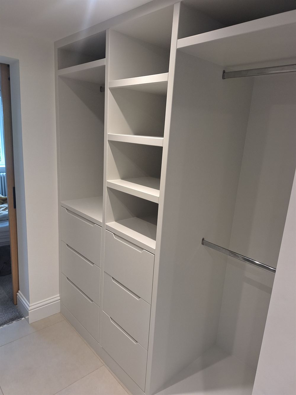 Fitted wardrobe interior finished in white, with drawers, shelving and hanging rails