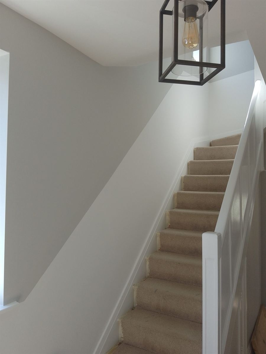 Bright white painted stairwell with a black lantern pendant light