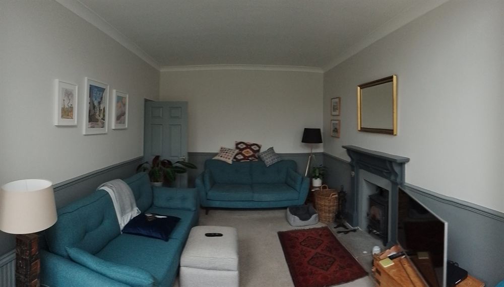 Finished living room with a two-tone painted wall, fireplace and teal sofas