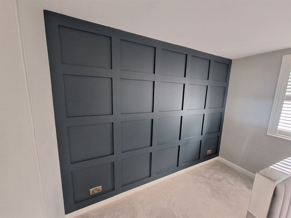 Bedroom wall finished with painted Shaker-style panelling in a deep blue-grey