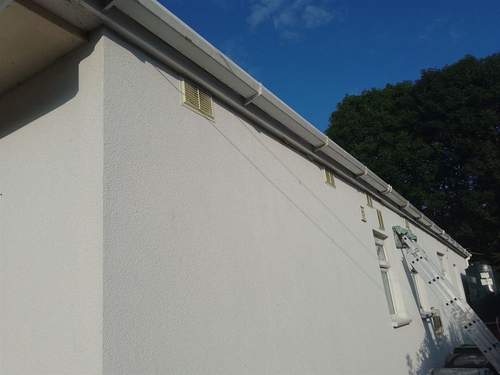 Repaired and repainted timber fascia board on a rendered house