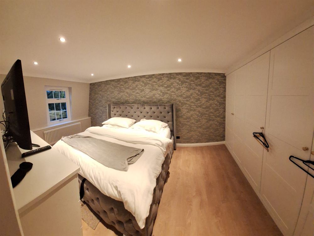 Bedroom feature wall in a textured patterned wallpaper behind an upholstered bed